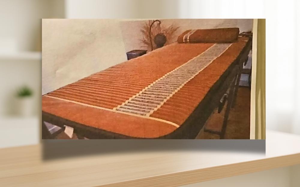 Manta Biomat posicionada sobre maca para sessão de terapia térmica com infravermelho e pedras