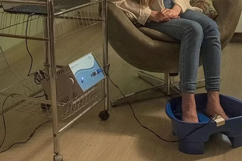 Mulher com os pés imersos em água durante sessão com o Hidrovitalis